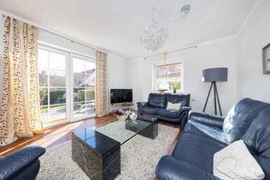 A living room with a glass coffee table, two sofas, a TV, and a floor lamp. - CBlue "Sandpiper" at Hohe Düne (Rostock)