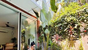 A person sitting by a pool with a book, surrounded by greenery and a modern house. - SolVanya by evaddo stays (Siolim)