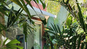 A person sitting by a pool with a book, surrounded by lush greenery and a modern house. - SolVanya by evaddo stays (Siolim)