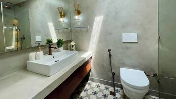 Een moderne badkamer met een grote spiegel, een witte wastafel, een douche en een toilet.