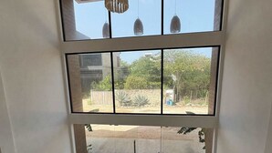 A room with large windows, a hanging light fixture, and two potted plants. - Modern 2BR Tulum Rooftop  Pool  Gym Coworking WiFi (Tulum)