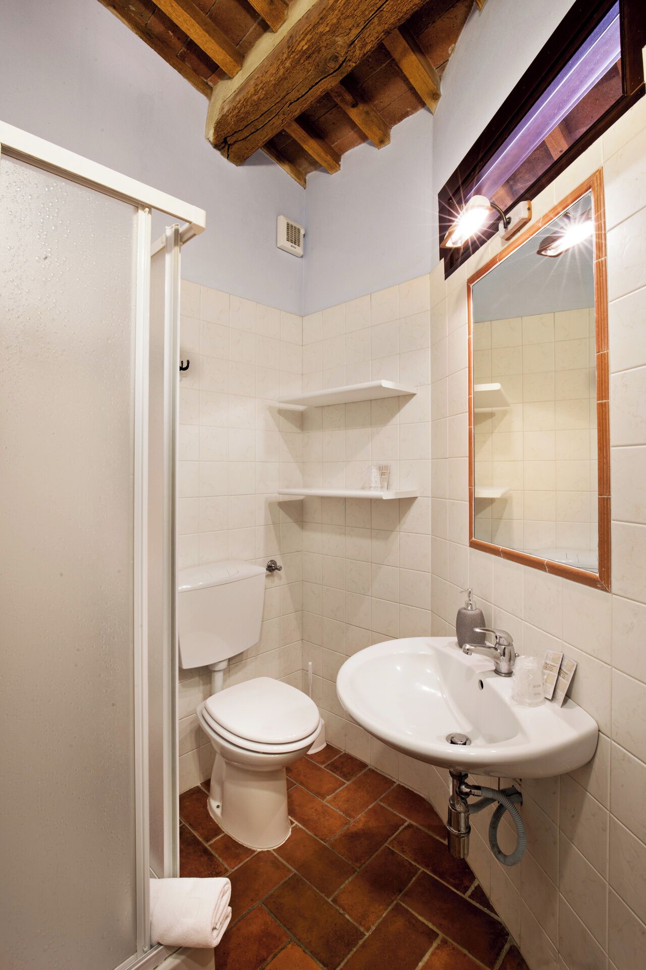 A bathroom with a white toilet, a sink with a mirror, and a shower area.