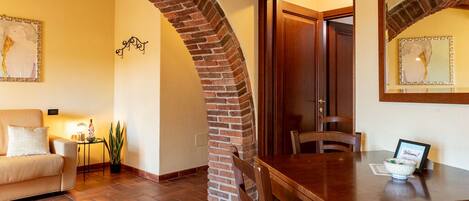 Un espacio acogedor con un arco de ladrillo, una mesa de comedor de madera y un sofá.