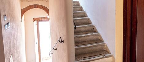 A staircase with a brick archway leading to a door.