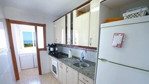 A kitchen with white cabinets, a granite countertop, and a refrigerator.