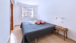 Une petite pièce lumineuse, avec un lit, une petite table et une fenêtre avec des rideaux.