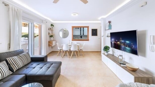 Un salon moderne avec un canapé, un téléviseur et un coin repas.