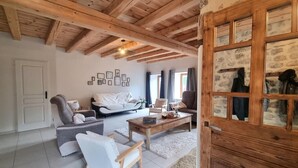 A cozy living room with a wooden ceiling, a sofa, a chair, and a coffee table. - Renovated country house, ideal for 10, natural setting and modern comfort (Gumières)