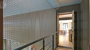 Un interior moderno con piso de madera, un separador de malla y vista hacia un comedor.