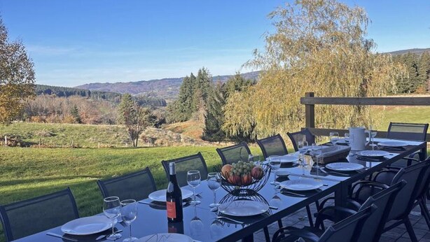 Comedor al aire libre con una mesa dispuesta para seis personas, con vistas a un paisaje pintoresco.