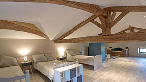 Un dormitorio tipo loft con vigas de madera a la vista, una cama, un sofá y un escritorio con cajones.