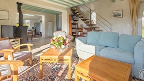A spacious living room with a sofa, wooden coffee table, and a bookshelf. A staircase leads to an upper level.