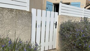 Una verja blanca con una cruz negra, una puerta azul y el número 192 en un edificio.