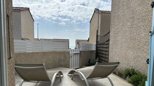 Un patio con dos sillones de descanso y una verja blanca.