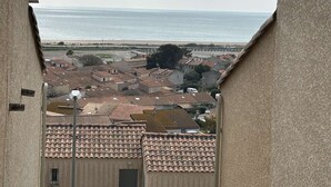 Vista de un pueblo costero con tejados de tejas rojizas y una playa al fondo.