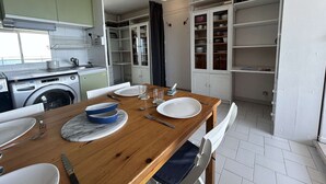 Une cuisine compacte avec une table à manger en bois pour deux personnes, un lave-linge et des placards intégrés.