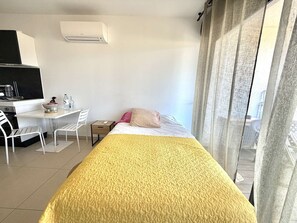 Ein Hotelzimmer mit Bett, Schreibtisch, Stuhl, Klimaanlage und Blick ins Freie.