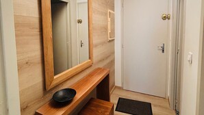 A hallway with a wooden bench, a large mirror, and a door. - Autrans - Renovated 6 pers apartment, 2 bedrooms, south terrace (Autrans-Méaudre en Vercors-Autrans)