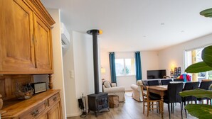 A cozy living room with a fireplace, wooden cabinets, a dining area, and a sofa. - Spacious house in Château-l'Évêque with 5 bedrooms and a game room (Château-l'Évêque)