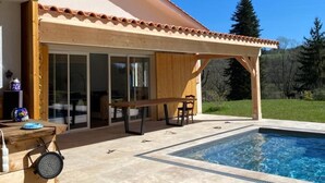 A poolside area with a wooden pergola, a pool, and a covered patio with a table and chairs. - Spacious house in Château-l'Évêque with 5 bedrooms and a game room (Château-l'Évêque)