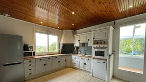 A modern kitchen with white cabinetry, a wooden ceiling, and large windows. - Rustic cottage in Vendée Marshes, near beaches (Sallertaine)