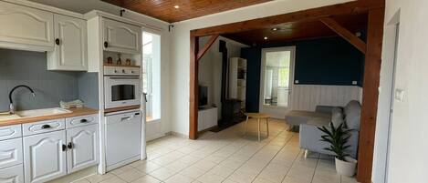 Une cuisine spacieuse avec des meubles blancs, un plafond en bois et un sol carrelé.