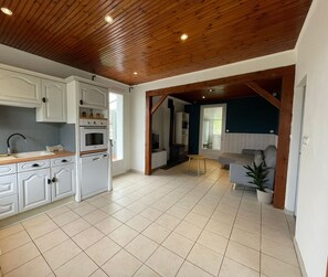 A spacious kitchen with white cabinets, a wooden ceiling, and a tiled floor.