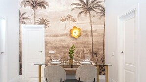 A dining area with a glass table, two chairs, and a wall mural of palm trees. - Cozy 3BD in Seville Center. Alfalfa (Seville)