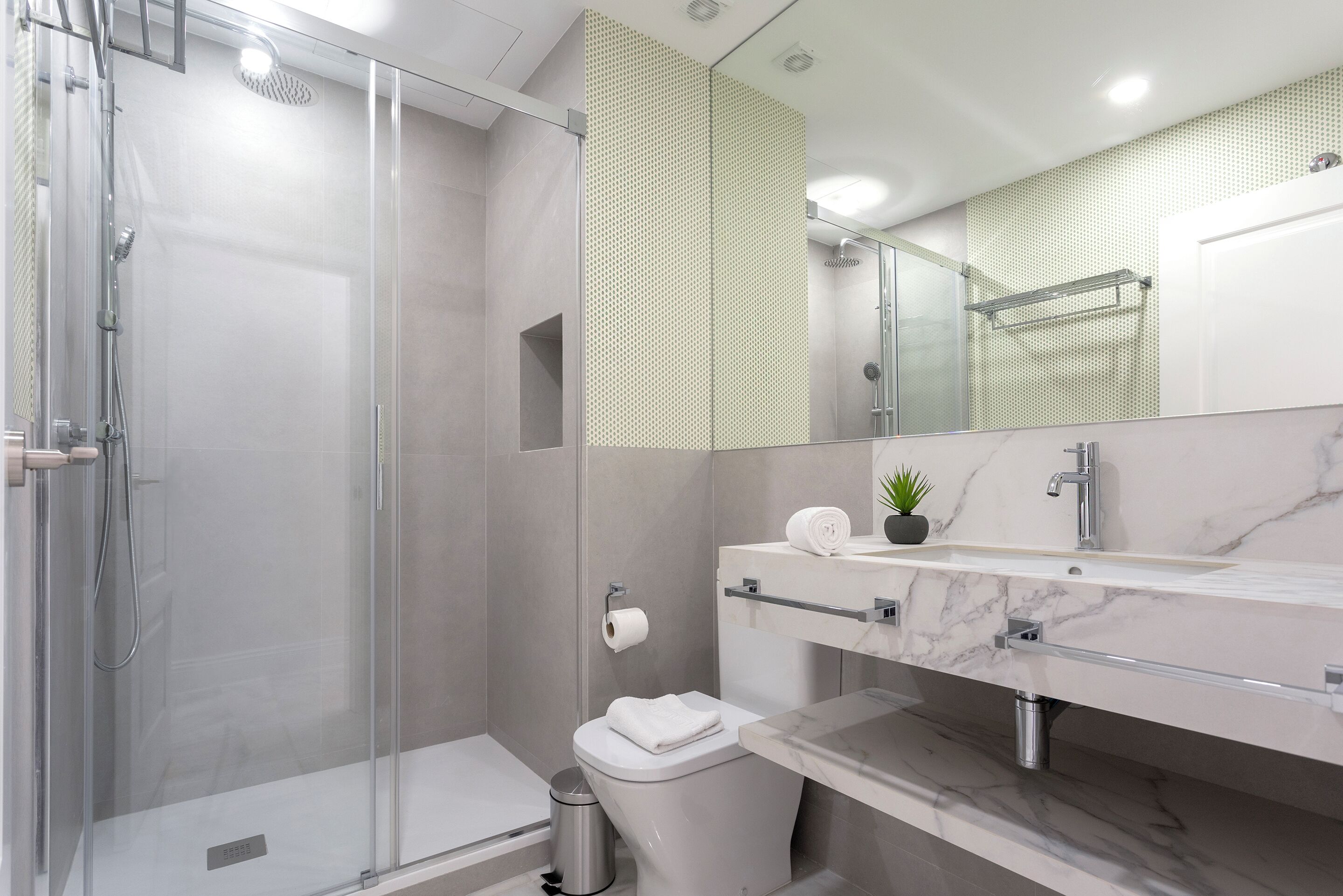 Une salle de bain moderne avec une douche à parois de verre, un lavabo en marbre et des toilettes.