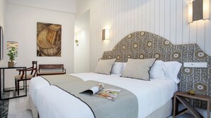 A neatly arranged hotel room with a large bed, a side table, a chair, and a wall-mounted lamp. - Cozy 3BD in Seville Center. Alfalfa (Seville)