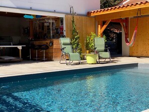 A swimming pool with lounge chairs and a bar area.