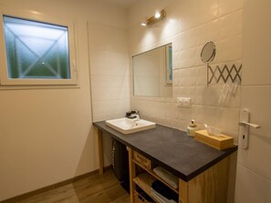 Een moderne badkamer met een wit wastafelmeubel, een spiegel en een raam.