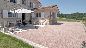 Una casa de dos pisos con un patio, mobiliario exterior y un camino de entrada de grava.
