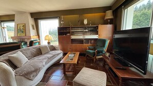 Un soggiorno con divano, poltrona, tavolino, libreria e televisore.