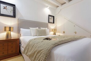 Un dormitorio con cama, mesitas de noche y lámparas de pared.