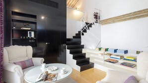 Un salon moderne avec un canapé, une table basse et un escalier agrémenté d’étagères.