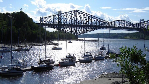 Eine Brücke über ein Gewässer, in der Nähe liegen Boote.