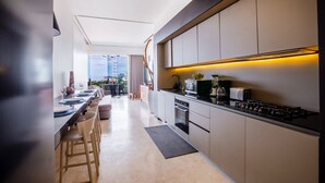 Una cocina moderna con una encimera larga, horno empotrado y un comedor con vistas a la ciudad.