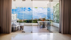 Un balcón moderno con puerta de vidrio, un sofá, una mesita y un comedor.