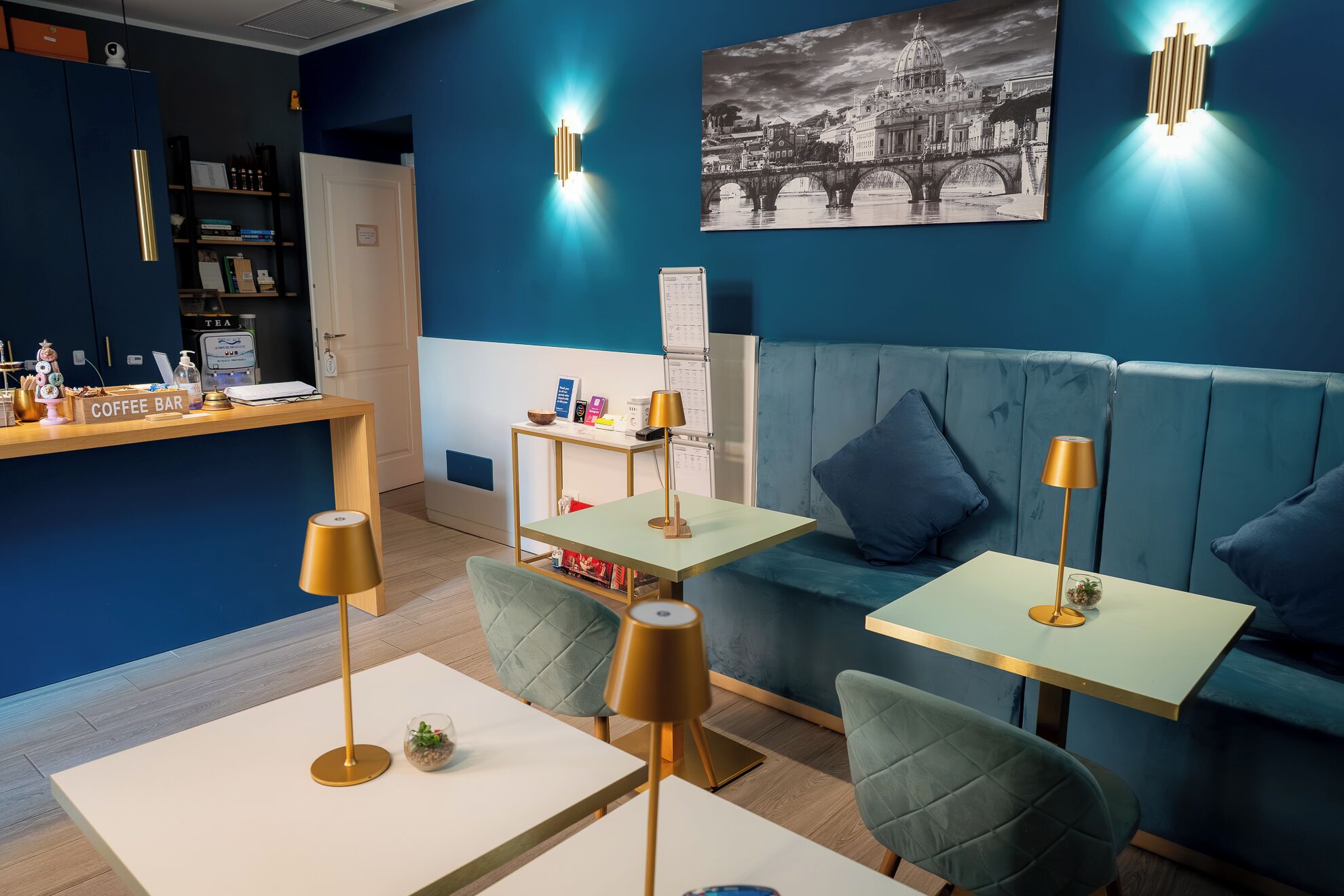 A modern hotel lobby with a coffee bar, seating area, and a wall-mounted artwork.