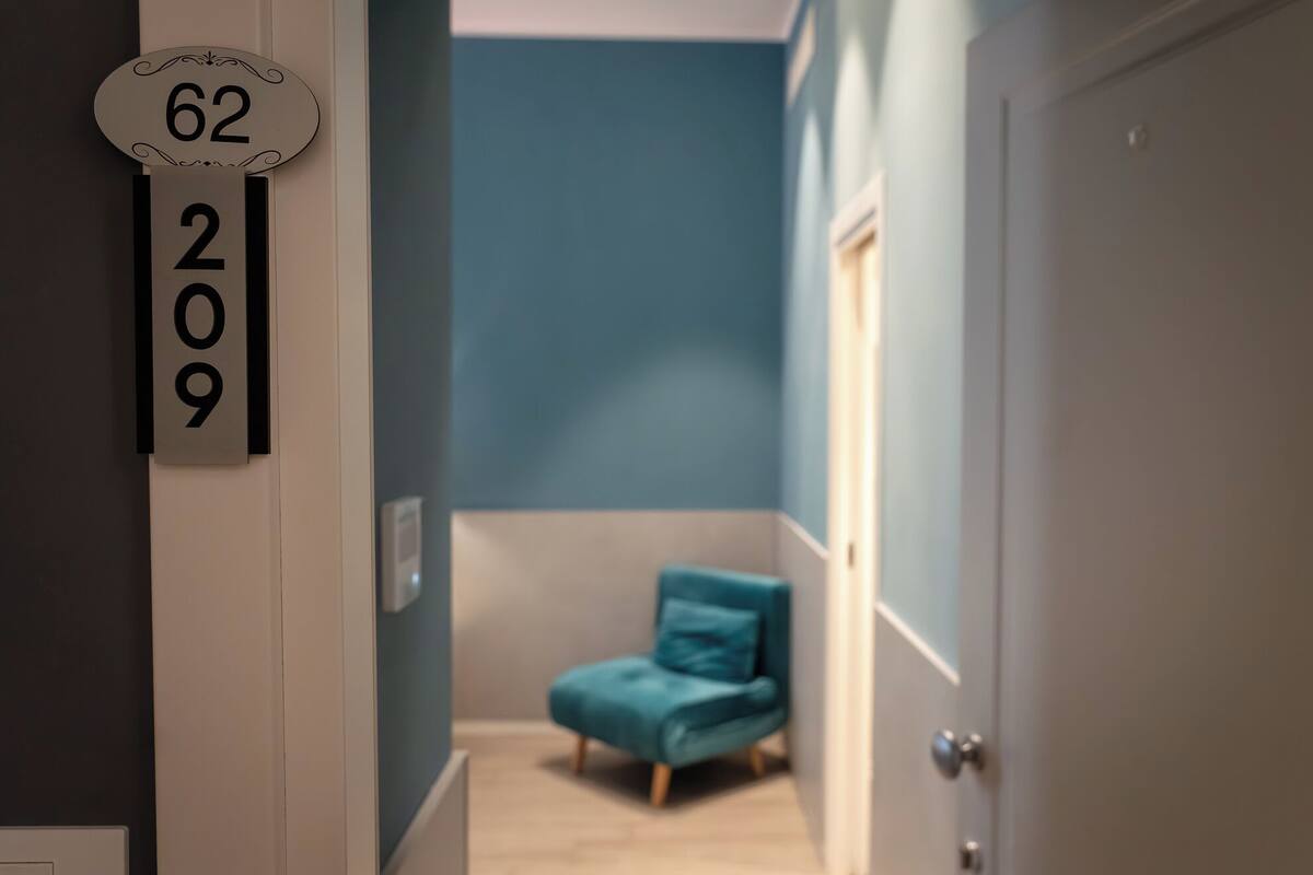 Un couloir avec un mur bleu, un fauteuil turquoise et une porte.