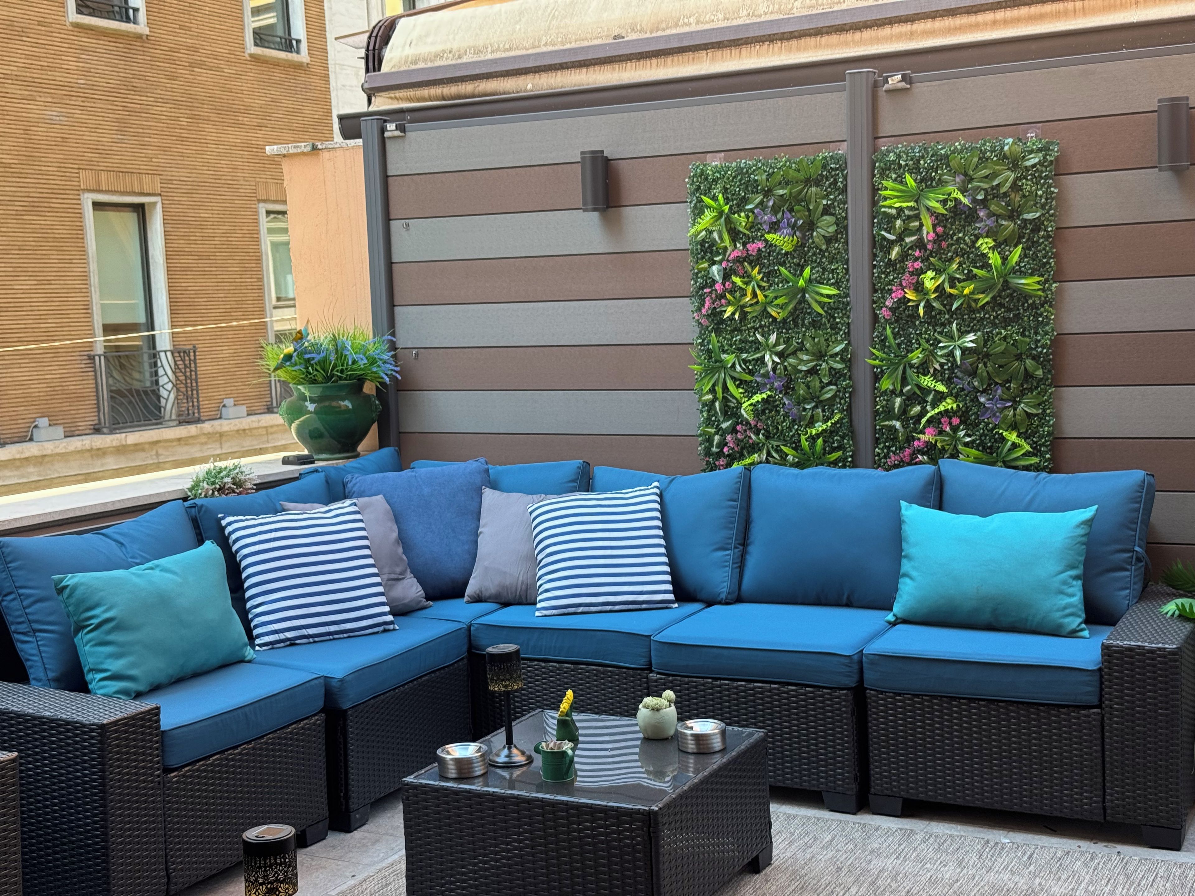Un sofá modular con cojines azules, una mesa de centro de mimbre y una planta en maceta.