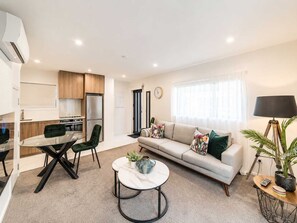 A modern living space with a dining area, a sofa, a coffee table, and a lamp.