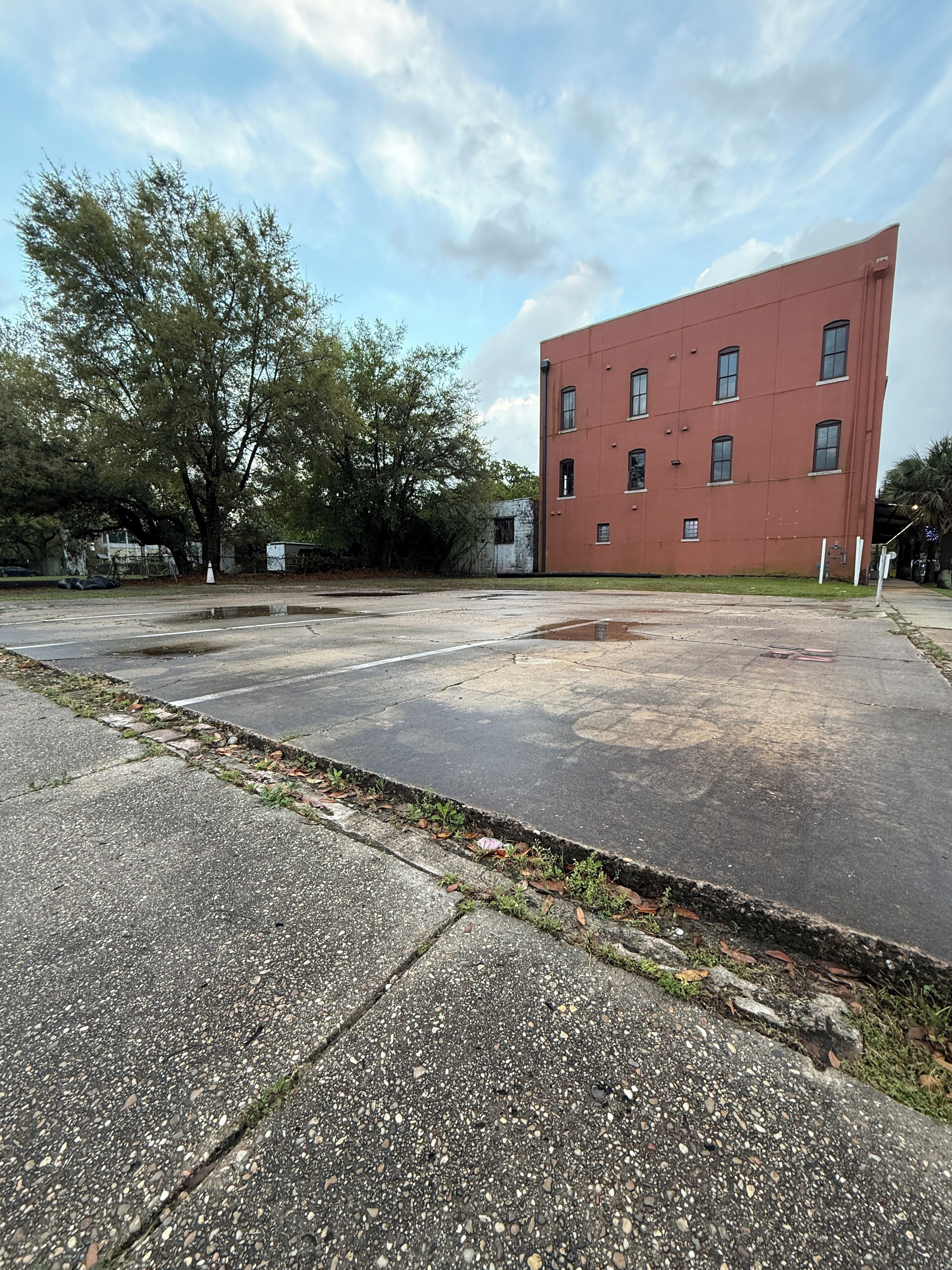 A large, empty parking lot with a red building in the background.