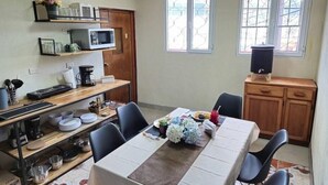 Zona pranzo con tavolo apparecchiato per quattro, microonde, macchina del caffè e dispenser di acqua.