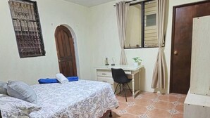 Una camera da letto con un letto, una scrivania, una sedia e un armadio.