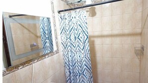 Un bagno con doccia, lavandino e specchio.