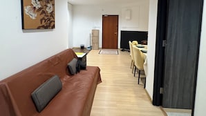 Un salon moderne avec un canapé marron, un coin repas comprenant une table et des chaises, et un grand tableau accroché au mur.