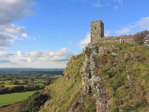 Un castello di pietra su una collina erbosa, con vista panoramica sulla campagna circostante.