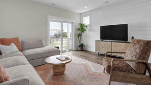 Ein modernes Wohnzimmer mit Sofa, Sessel, Couchtisch, Fernseher und einem Balkon mit Blick.